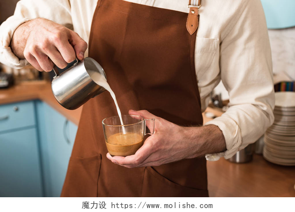 咖啡师正在往咖啡杯中倒入牛奶咖啡师在咖啡中倒牛奶的裁剪视图